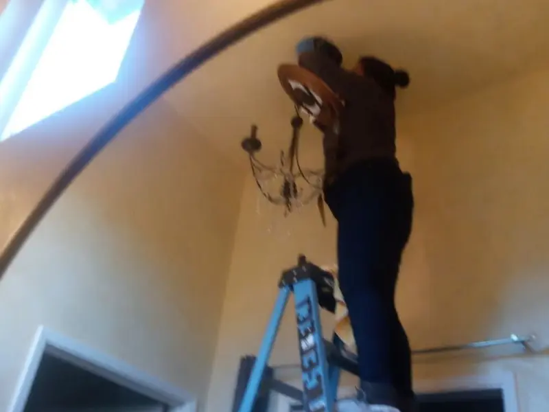 Electrician installing a chandelier in a Lake Shore residence
